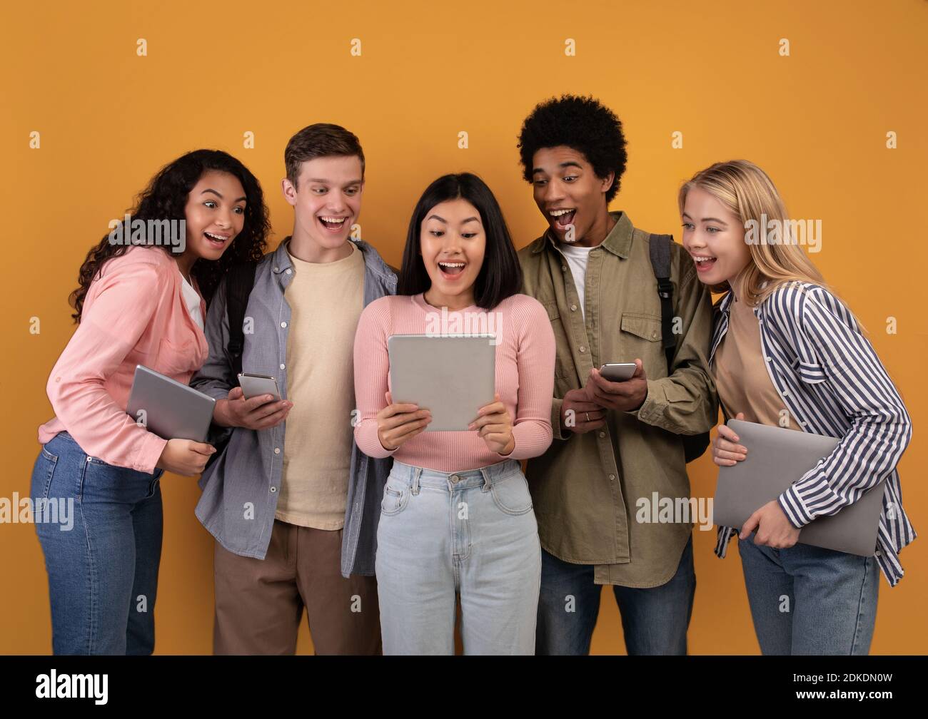 Moderne Gadgets, soziale Netzwerke und Bildung. Schockiert fröhlich junge multiethnische Studenten suchen in digitalen Tablet Stockfoto