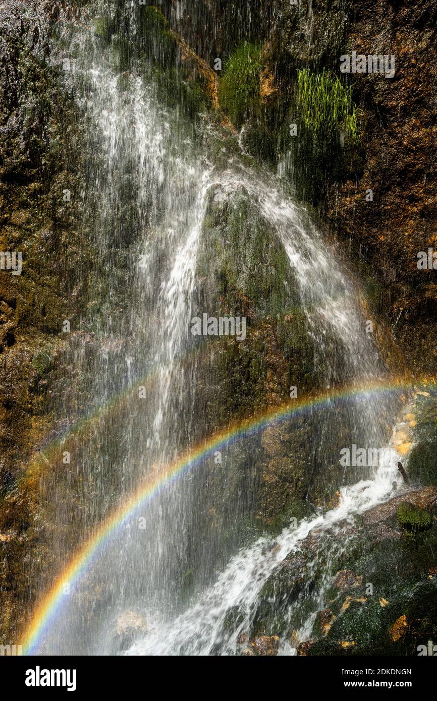 Regenbogen am Dalfaz Wasserfall unterhalb des Dalfaz Klettersteigs am Achensee im Rofangebirge. Wasser fällt in die Felswand und bildet einen wunderbaren kleinen doppelten Regenbogen in der Sonne. Stockfoto