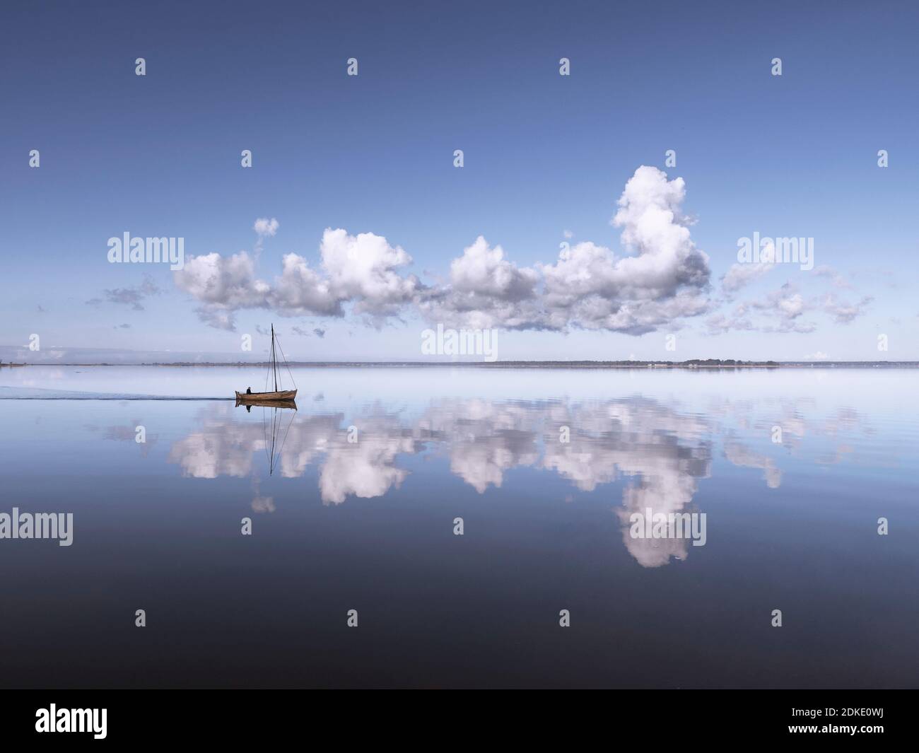 Ein altes Holzboot bricht die perfekte Spiegelung eines Wolkenbildung auf dem Wasser [M] Stockfoto
