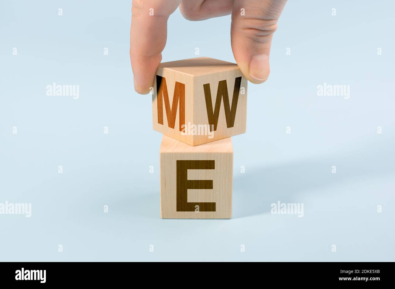 Hand Flip Holzwürfel mit mir oder wir auf blauem Hintergrund. Teamwork-Konzept. Hand dreht Würfel und ändert das Wort MICH zu UNS Stockfoto