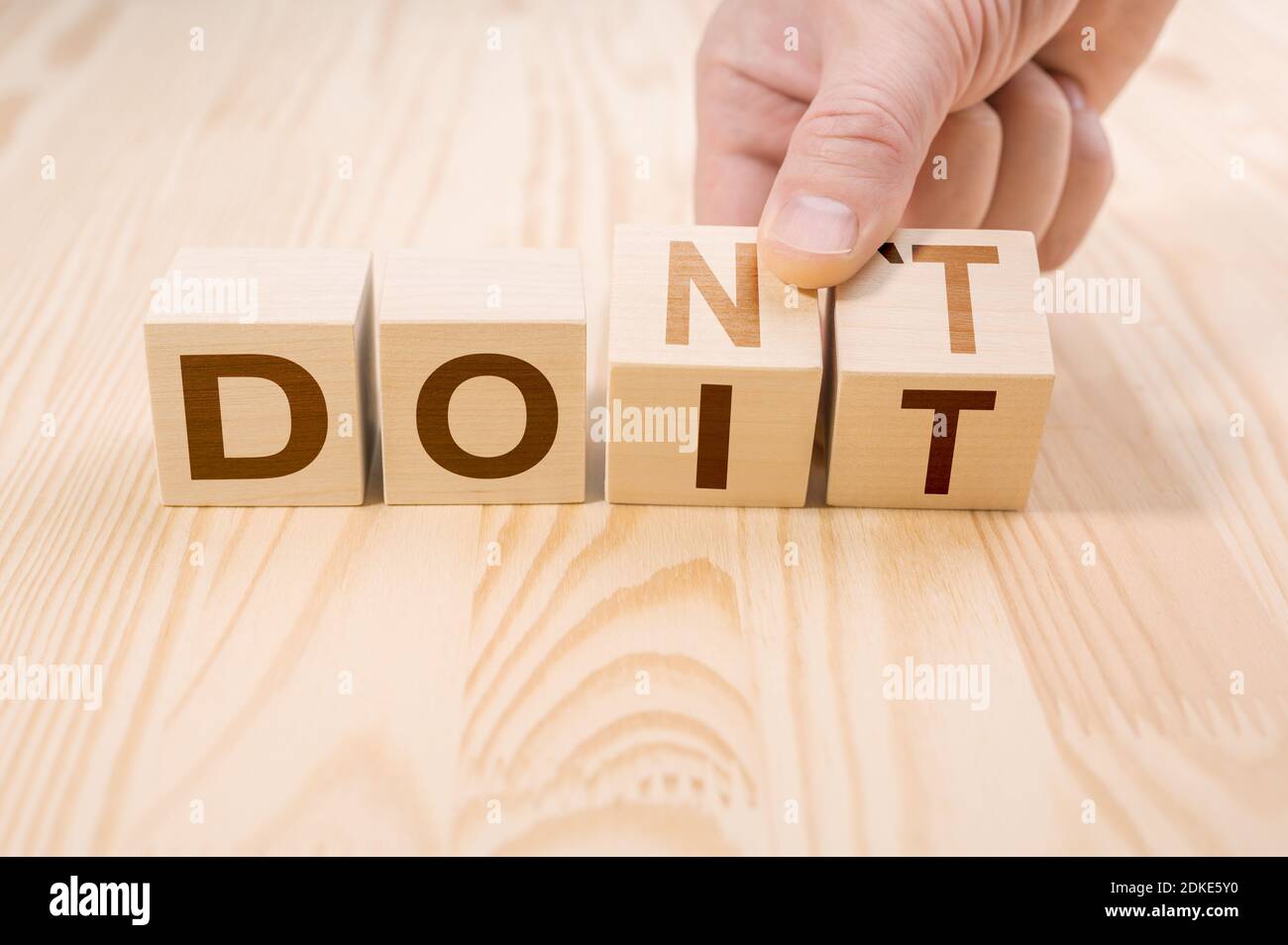 Hand dreht zwei Würfel mit Buchstaben, Ändern des Wortes nicht in tun es auf hölzerner Oberfläche. Karriereentwicklung, Risiko, persönliche Entwicklung und Motivati Stockfoto