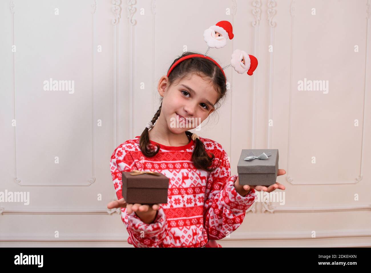Kind Mädchen mit Schachteln von Geschenken für das neue Jahr. Ein Teenager-Mädchen hält zwei Boxen mit Geschenken. studio Foto. Stockfoto