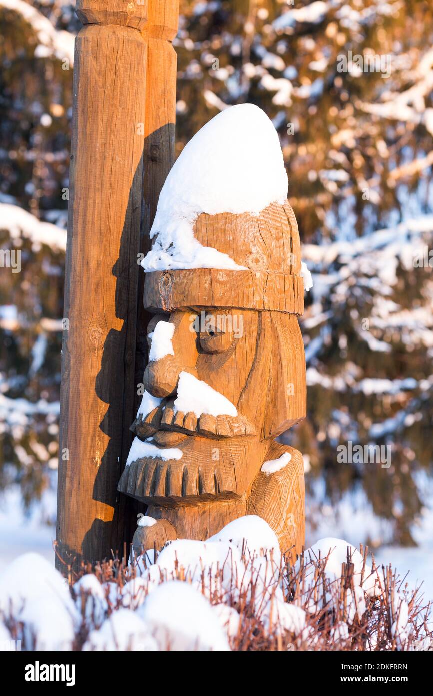 Holzskulptur des Märchencharakters, ein bärtiger Mann bedeckt mit Schnee bei Sonnenuntergang frostigen sonnigen Wintertag Stockfoto