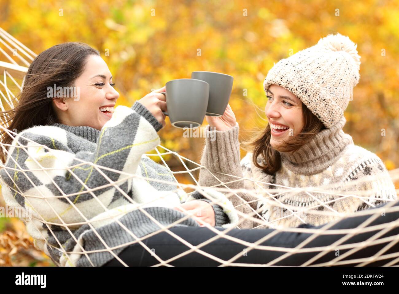 Zwei glückliche Freunde toasten mit Kaffeetassen im Herbsturlaub In einem Wald Stockfoto
