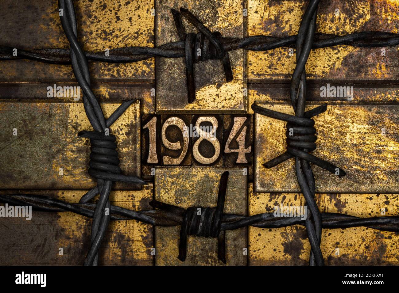 1984 umrandet von Stacheldraht auf grauem, strukturiertem korrodiertem Kupfer Und Gold Hintergrund Stockfoto