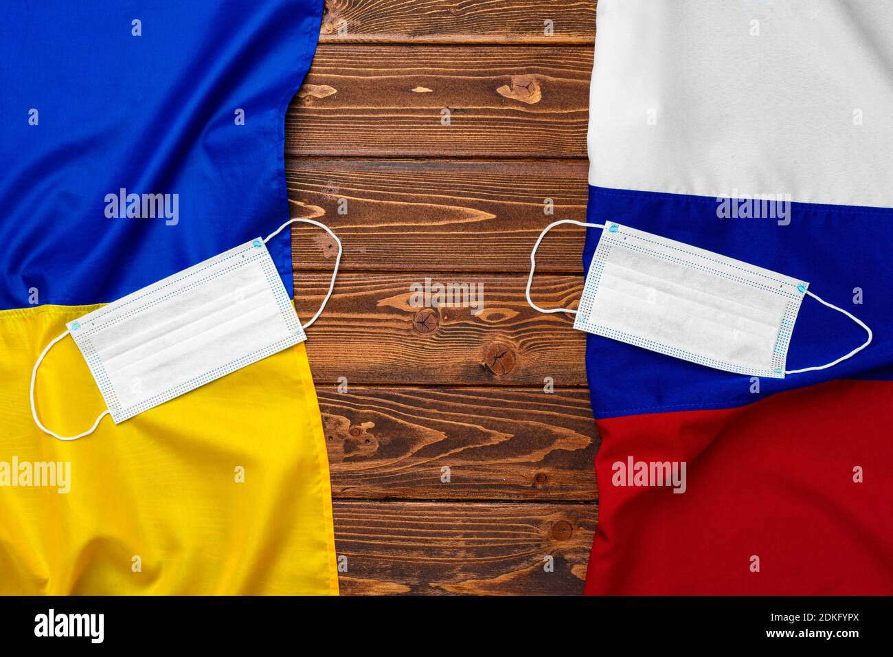 Flaggen von Russland und der Ukraine auf hölzernen Hintergrund mit medizinischen Masken Stockfoto