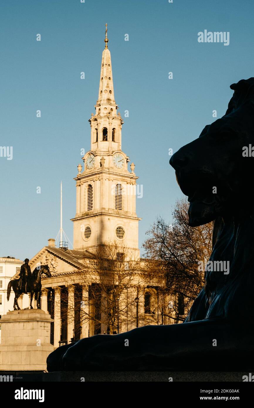 Trafalgar Square, London, Großbritannien. Dezember 2020. Eine Löwenstatue am Fuß der Nelson-Säule in Silouette an einem sonnigen Wintertag in London mit St. Martin's-in-the-Field im Hintergrund. Kredit: Tom Leighton/Alamy Live Nachrichten Stockfoto