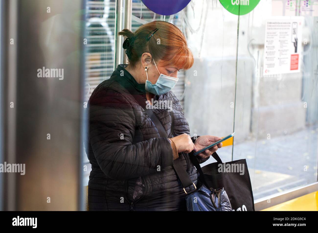 Frau an der Bushaltestelle mit ihrem Smartphone, Barcelona. Stockfoto