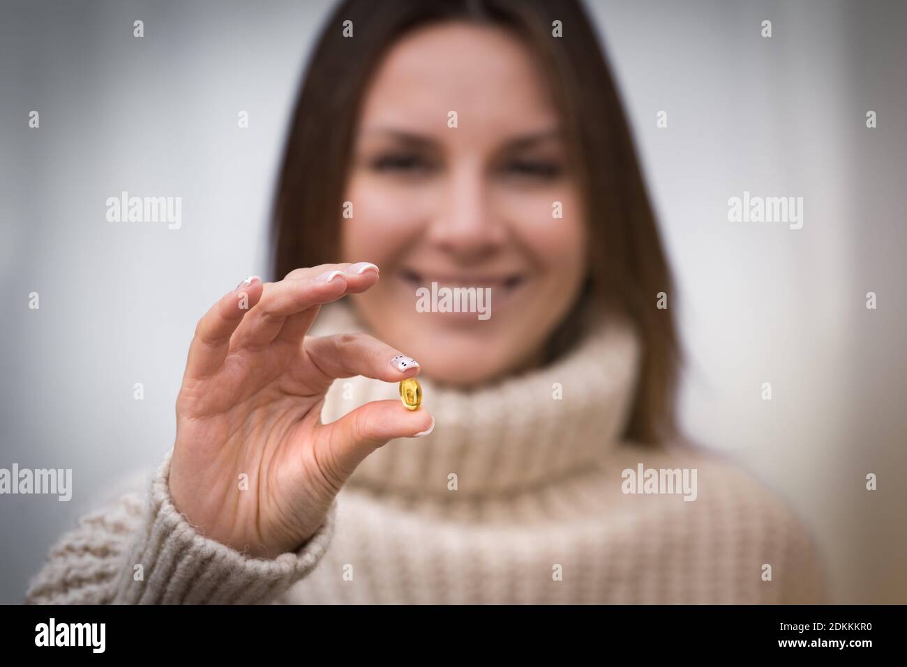 Junge glückliche Frau hält Fischöl Pille oder Vitamin D Ergänzung. Stockfoto