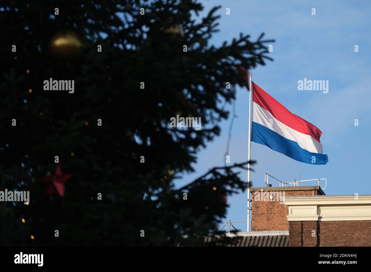 Eine holländische Nationalflagge flattert an einem Weihnachtsbaum vorbei, der am 15. Dezember 2020 in Den Haag, Niederlande, auf dem Plein Platz steht. Die neue fünfwöchige landesweite "harte Sperre" wurde für fünf Wochen verhängt, wo Schulen, alle nicht notwendigen Geschäfte, Friseure, Museen, Theater und Fitnessstudios geschlossen sind, um die steigende Zahl von Coronavirus-Fällen einzudämmen. Quelle: Yuriko Nakao/AFLO/Alamy Live News Stockfoto