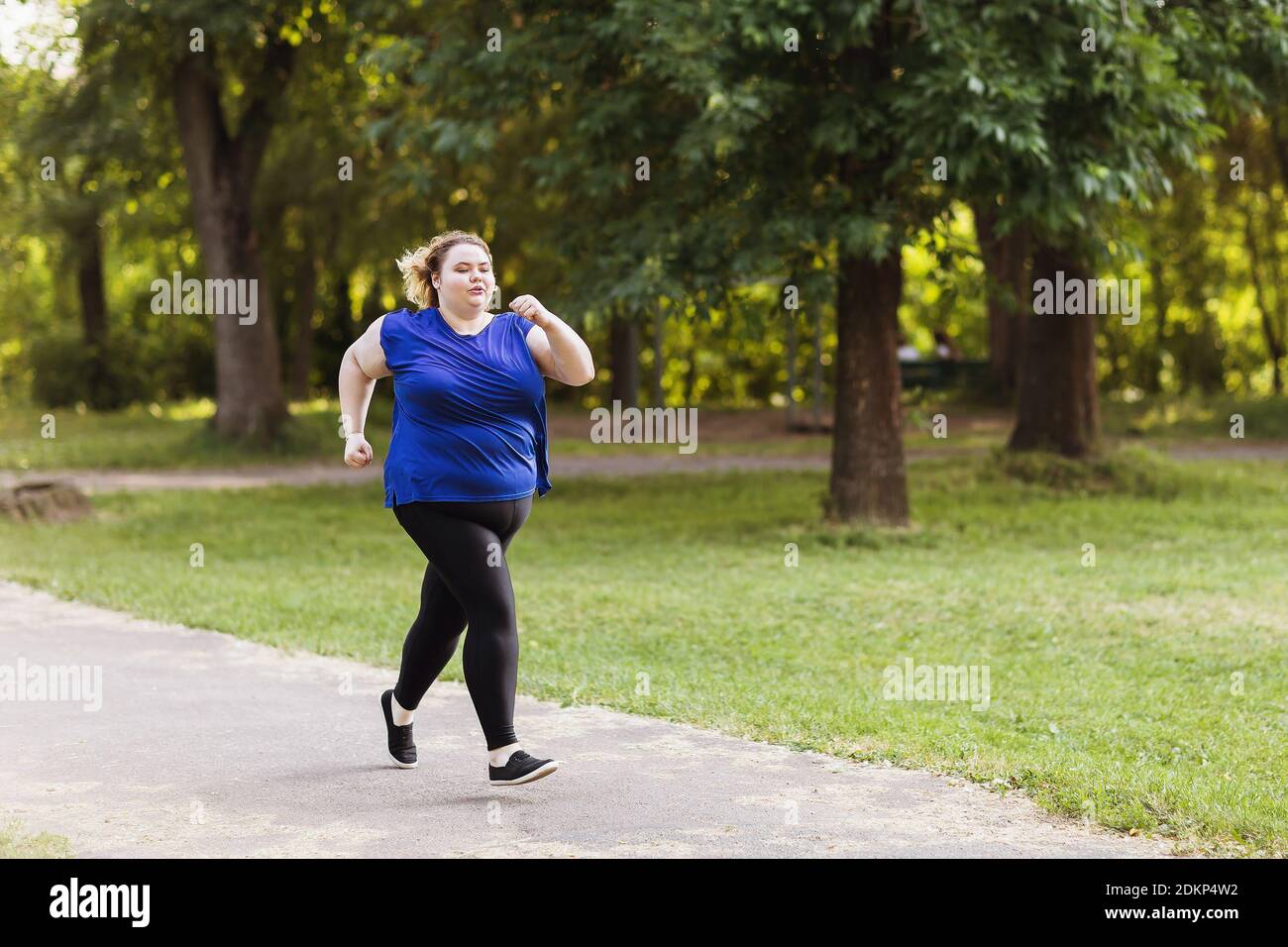 Eine junge Blondine von großen Größen läuft im Park. Gesundes Lifestyle-Konzept. Stockfoto