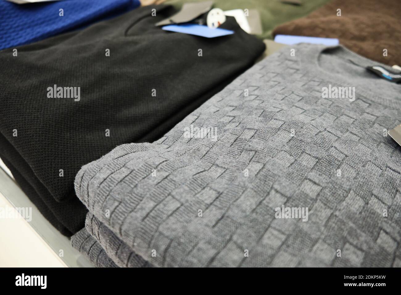 Herren Strickpullover in Pastellfarben auf Ladentisch gestapelt Stockfoto