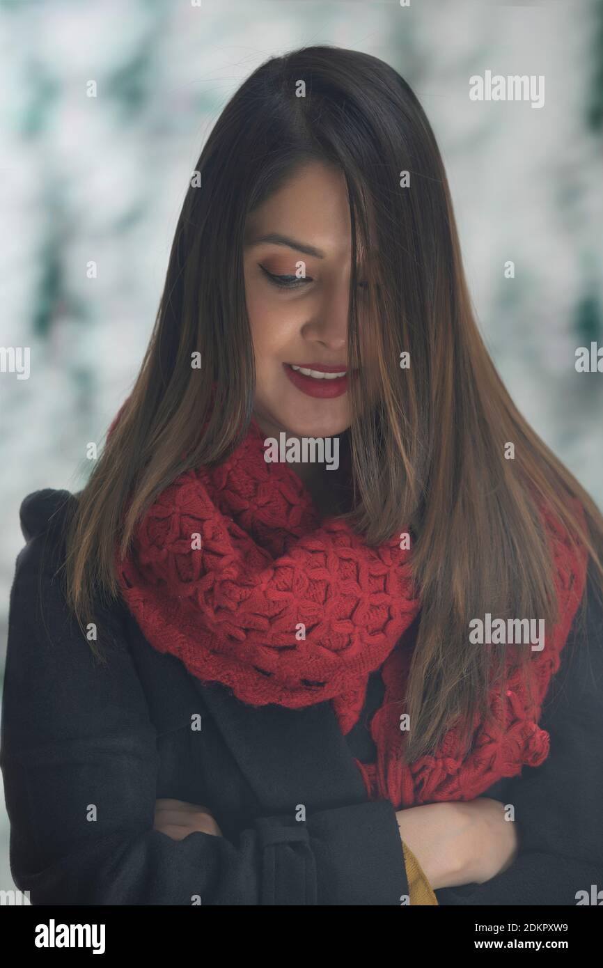 EINE FRAU IN WINTERKLEIDUNG MIT GEFALTETEN ARMEN STEHEN UND BLICK NACH UNTEN Stockfoto