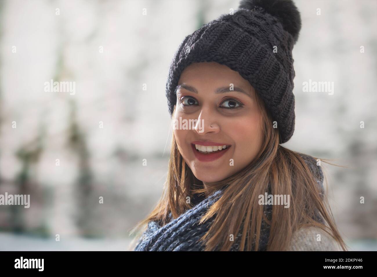 PORTRÄT EINER FRAU IN WINTERKLEIDUNG UMDREHEN UND LÄCHELND Stockfoto