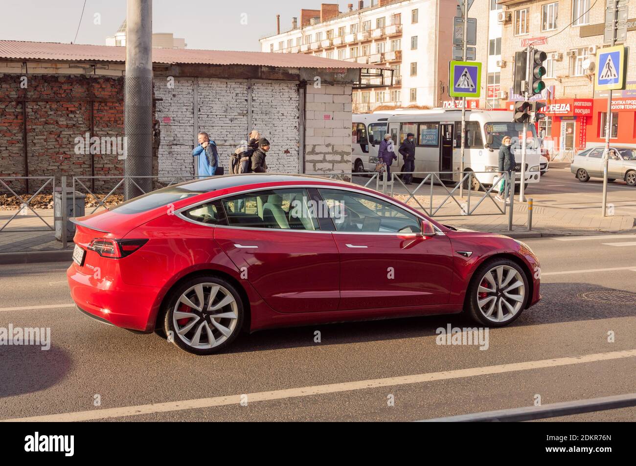 Red Tesla Car Model 3 auf der Stadtstraße in Ein sonniger Tag Stockfoto