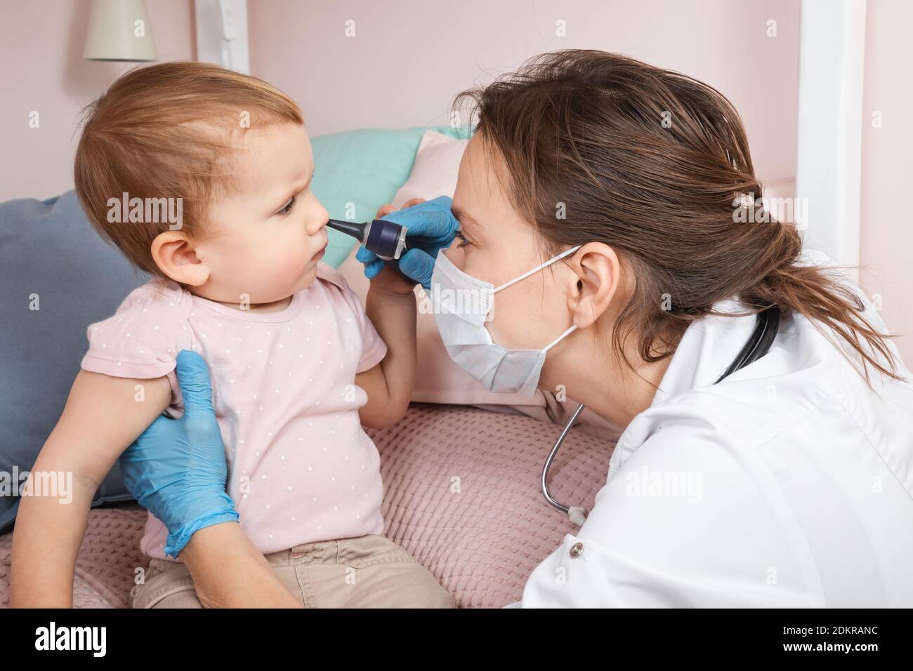 Kinderarzt untersucht die Nase des Babys zu Hause während der Coronavirus COVID-19 Pandemie Quarantäne. Arzt mit Otoskop (Auriskop), um Nasenpass zu überprüfen Stockfoto