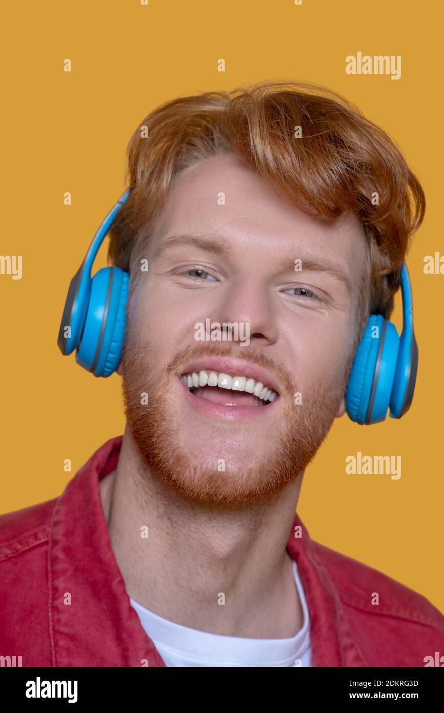 Junger Ingwer-Mann, der Musik hört und glücklich aussieht Stockfoto