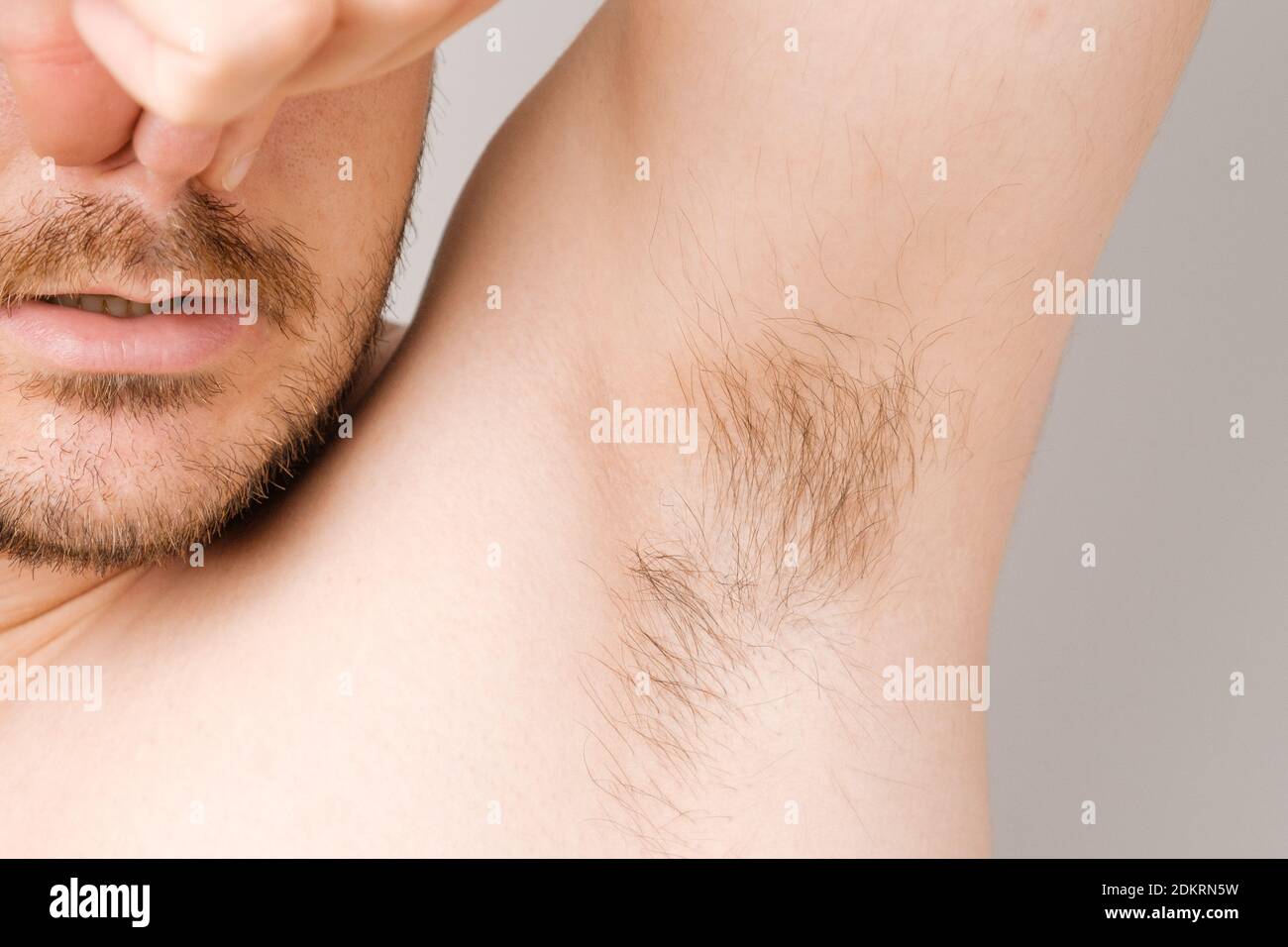 Nahaufnahme von Mann Achselhöhle mit langen unrasierte Haare und Kneifen Nase von schwitzigen schlechten Geruch Stockfoto