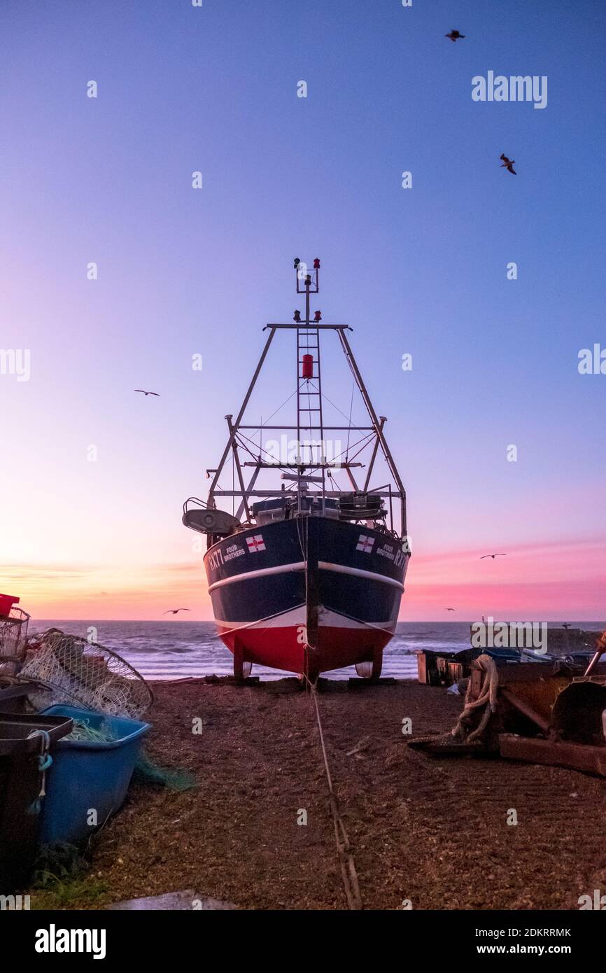 Hastings; East Sussex; Großbritannien. Dezember 2020. Farbenprächtiger Sonnenaufgang, während Möwen an einem luftigen, aber milden sonnigen Tag über dem Fischerboot schweben. Carolyn Clarke/Alamy Live News Stockfoto