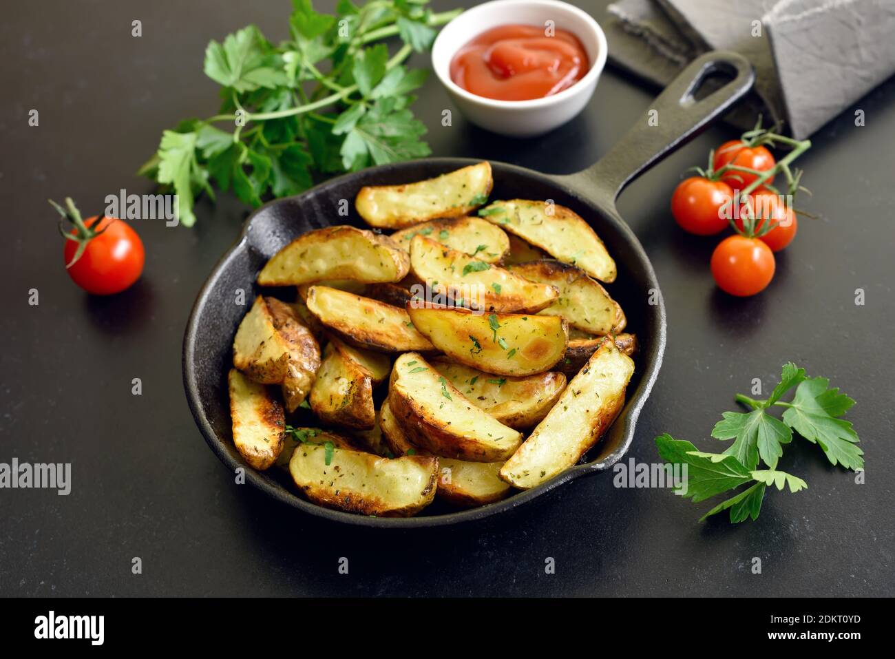 Bratkartoffelkeile mit Gewürzen in der Pfanne Stockfoto
