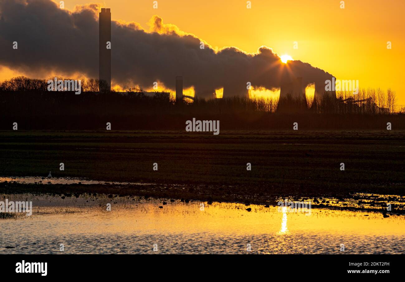 Sonnenaufgang bei Drax. Ein Wintermorgen mit der Sonne, die kurz vor dem Aufgehen hinter einer Wasserdampfspur steht, die aus den Kühltürmen eines Kraftwerks aussendet Stockfoto