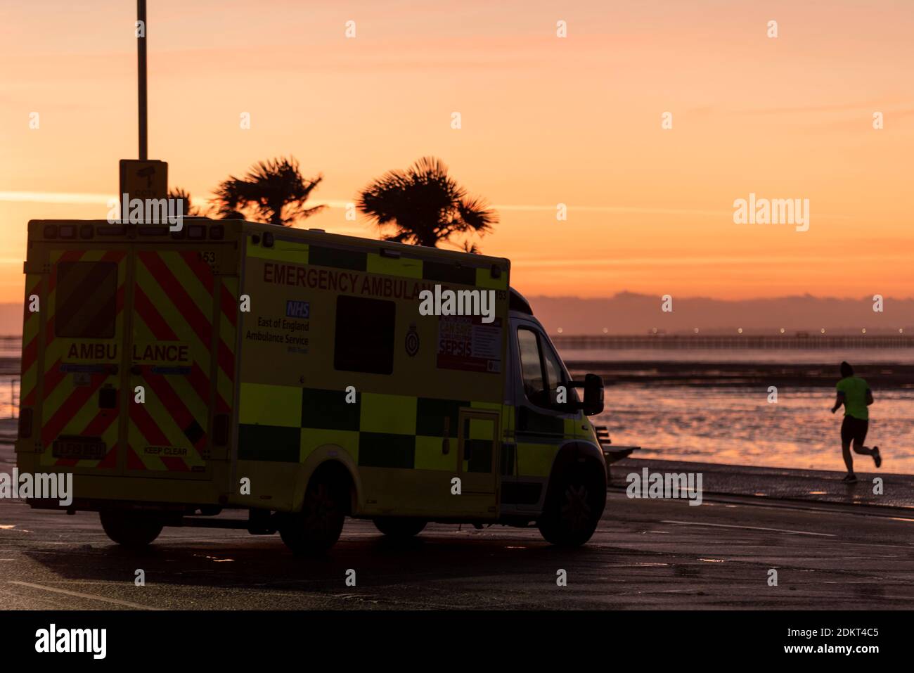 Southend on Sea, Essex, Großbritannien. Dezember 2020. Zusammen mit London haben einige Gebiete von Essex nach Mitternacht den Status „Very High Alert“ der Stufe 3 erreicht. Vor der zweiten Sperre hatte sich die einheitliche Behörde von Southend on Sea entschieden, in Tier 1 zu bleiben, während die umliegenden Gebiete von Essex in Tier 2 übergingen, aber dieses Mal wurde der Bezirk in Tier 3 platziert. Die Leute trainieren entlang der Strandpromenade der Stadt und machen ihren Weg zur Arbeit oder zum Einkaufen. Ein Mann, der bei Sonnenaufgang an einer Ambulanz entlang der Promenade joggt Stockfoto