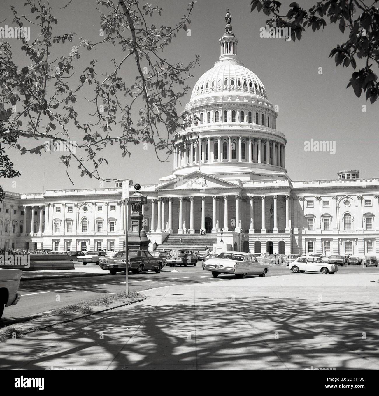 Historische Autos aus der Zeit der 1960er Jahre parkten auf einer Straße am Capitol Hill vor dem Capitol Building der Vereinigten Staaten in Washington DC, USA. Im neoklassizistischen Stil erbaut, mit einer Kuppel und großen Säulen, ist es Sitz des US-Kongresses, der Legislativabteilung der Bundesregierung und beherbergt die Kammern des Oberkörpers, des Senats und des Unterkörpers, des Repräsentantenhauses, die beiden Organe, die den Legislativzweig der amerikanischen Regierung bilden. Stockfoto