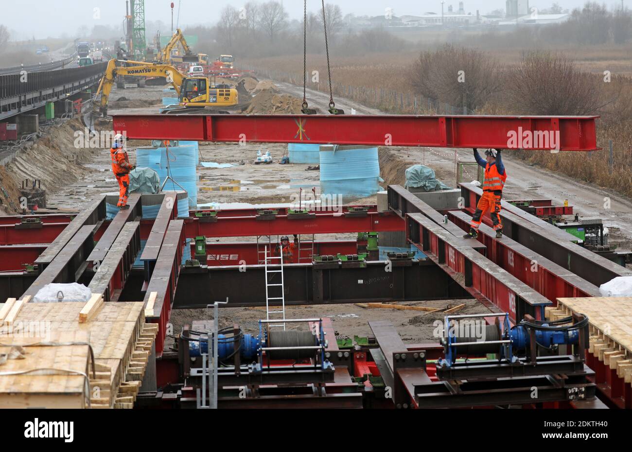 Tribsees, Deutschland. Dezember 2020. Die Arbeiten an der neuen Brücke auf der abgesauerten BALTISCHEN Autobahn A 20 laufen auf Hochtouren, links rollt der Verkehr über die provisorische Brücke. Für die fast 800 Meter lange Nordhälfte der Brücke werden insgesamt 308 Bohrpfähle in den Boden getrieben, 254 sind bereits im Boden. Die Arbeiten begannen im April 2020 und liegen im Zeitplan. Die erste Hälfte der Brücke soll im Herbst 2021 fertiggestellt werden, die Fertigstellung der A20 ist für 2023 geplant. Die auf einem Moor gebaute Autobahn war im Herbst 2017 eingestürzt. Quelle: Bernd Wüstneck/dpa/Alamy Live News Stockfoto