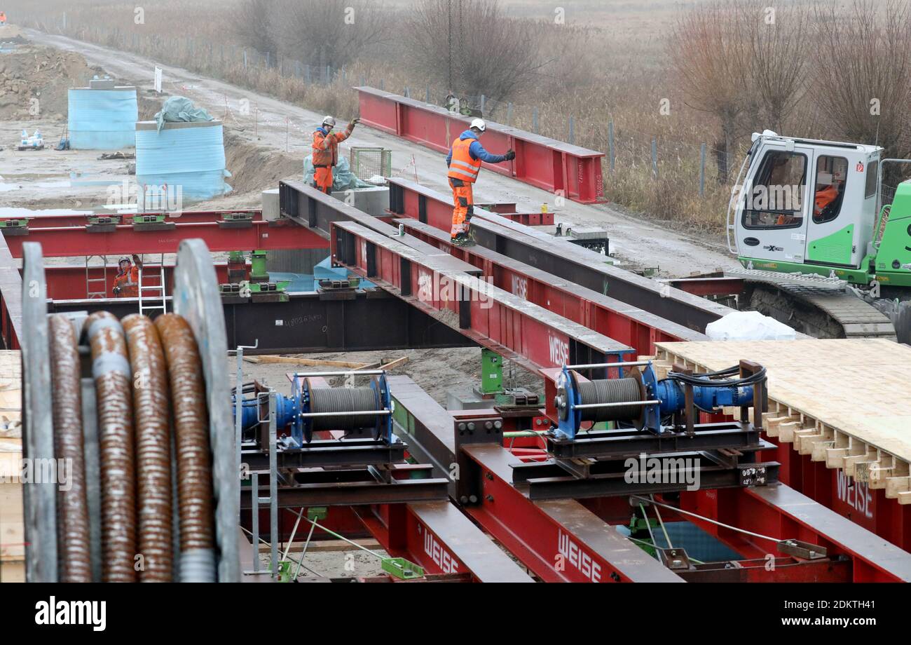 Tribsees, Deutschland. Dezember 2020. Die Arbeiten an der neuen Brücke auf der abgesauerten BALTISCHEN Autobahn A 20 laufen auf Hochtouren, links rollt der Verkehr über die provisorische Brücke. Für die fast 800 Meter lange Nordhälfte der Brücke werden insgesamt 308 Bohrpfähle in den Boden getrieben, 254 sind bereits im Boden. Die Arbeiten begannen im April 2020 und liegen im Zeitplan. Die erste Hälfte der Brücke soll im Herbst 2021 fertiggestellt werden, die Fertigstellung der A20 ist für 2023 geplant. Die auf einem Moor gebaute Autobahn war im Herbst 2017 eingestürzt. Quelle: Bernd Wüstneck/dpa/Alamy Live News Stockfoto