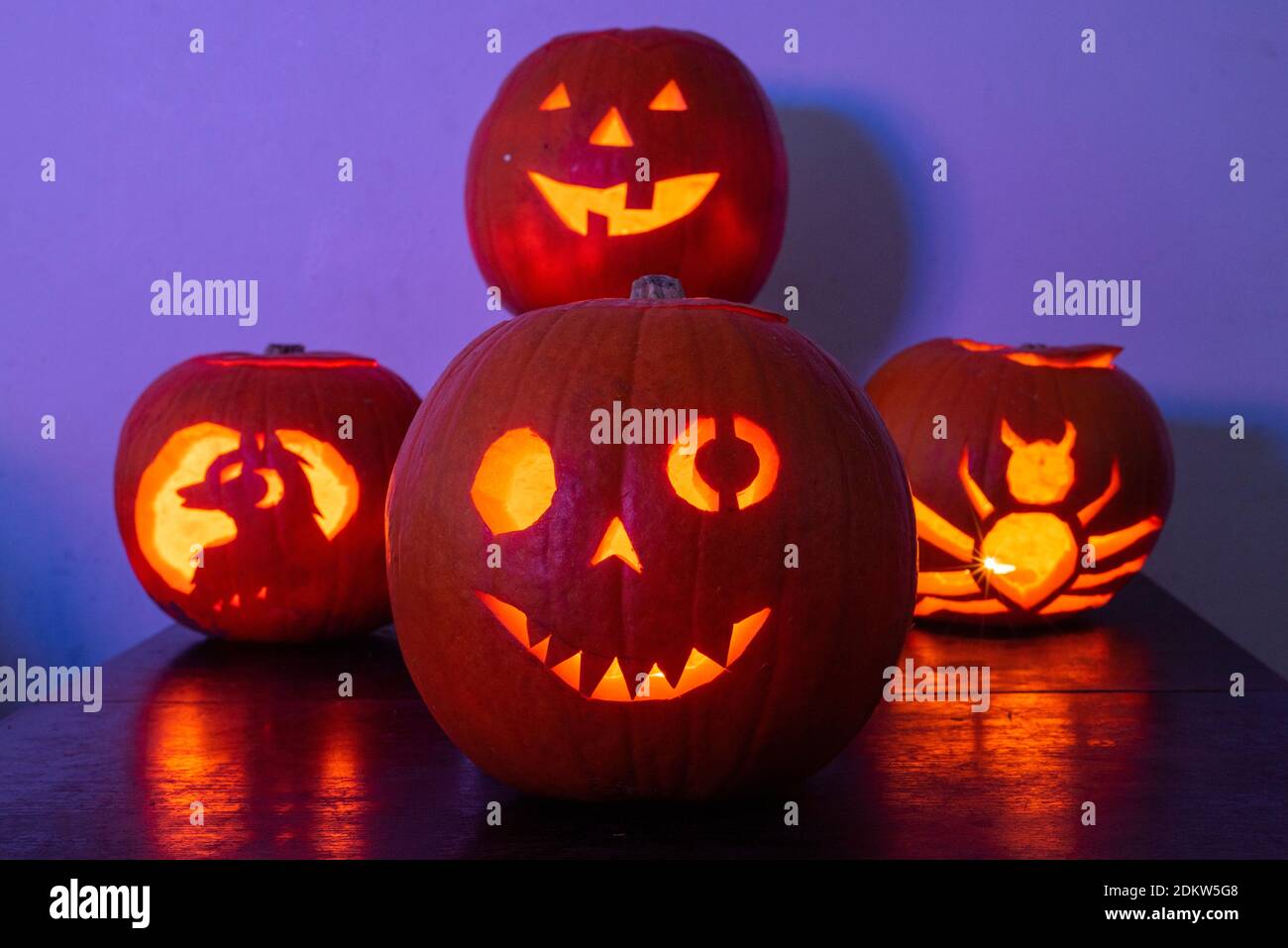 Vier beleuchtete Jack O Laterne geschnitzte Kürbisse glühen an Halloween Nacht Stockfoto