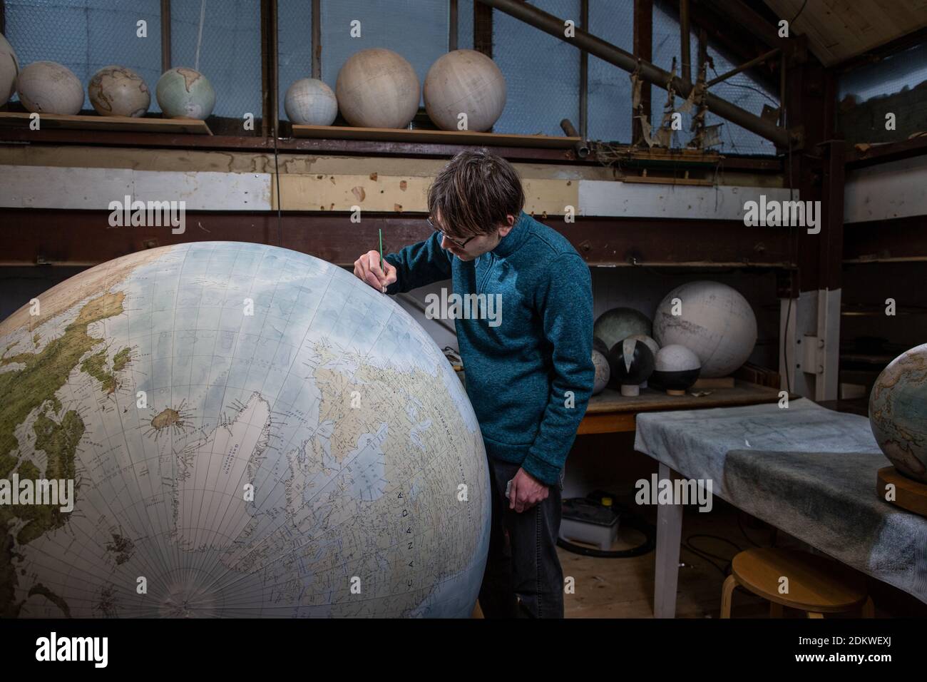 Eine Menschenhand malt einen Chruchill Globe, den größten handgefertigten Globus der Welt mit einem Durchmesser von 50 cm, bei Bellerby & Co in Stoke Newington, North London, UK Stockfoto