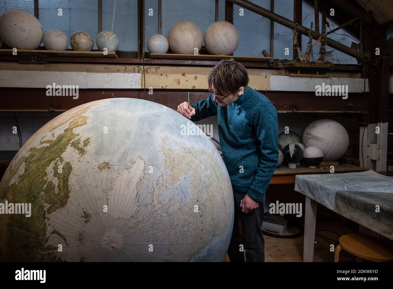 Eine Menschenhand malt einen Chruchill Globe, den größten handgefertigten Globus der Welt mit einem Durchmesser von 50 cm, bei Bellerby & Co in Stoke Newington, North London, UK Stockfoto