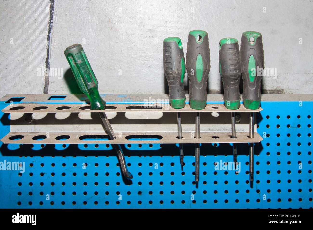 Ein Satz schmutziger grüner Schraubendreher hängt in der Garage Stockfoto