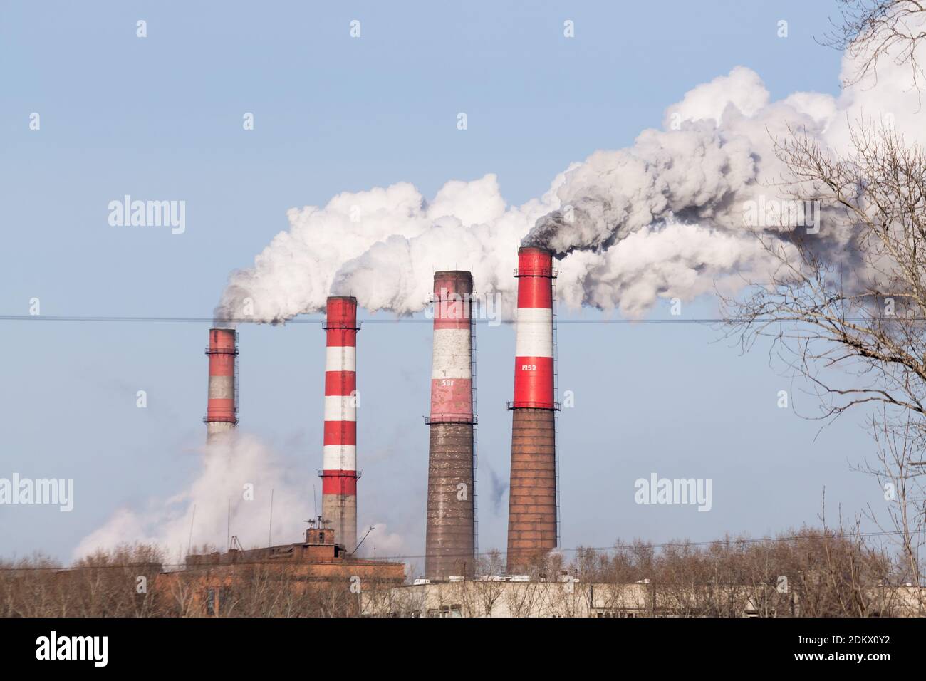 Die Industrieschornsteine mit starkem Rauch auf blauem Himmel Hintergrund. Smokestack Verschmutzung in der Luft als Umweltproblem Stockfoto