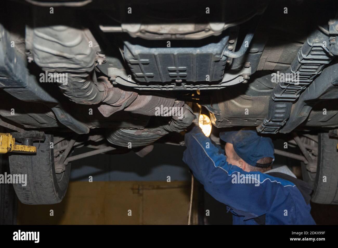 Ein Mechaniker mit einer Lampe untersucht den Boden der Auto Stockfoto