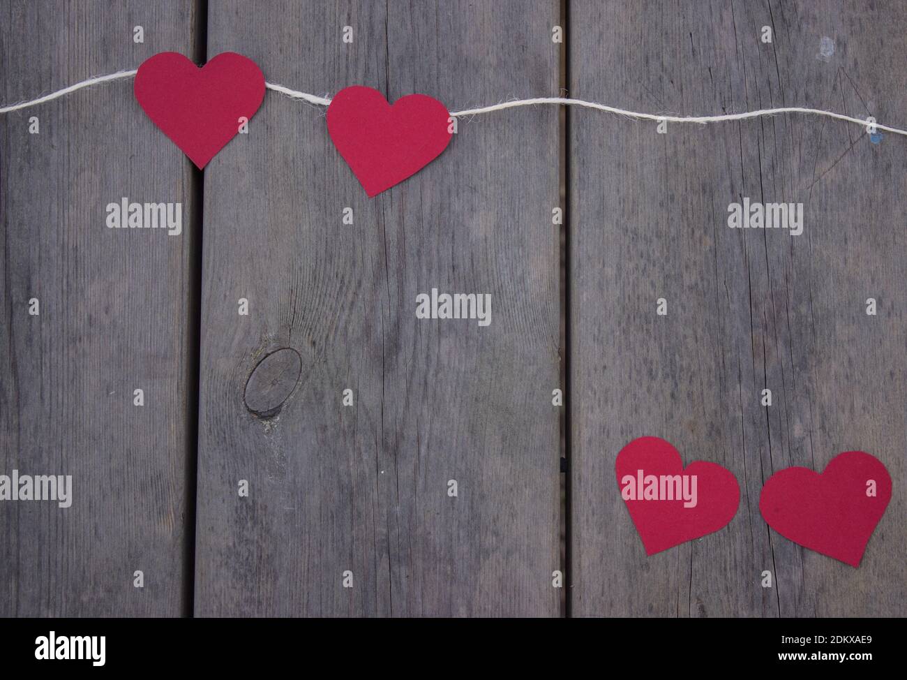 Draufsicht rote Herzen am Seil auf rustikalem Holzhintergrund. Valentinstag 2021. Für Text platzieren, Platz kopieren. Stockfoto