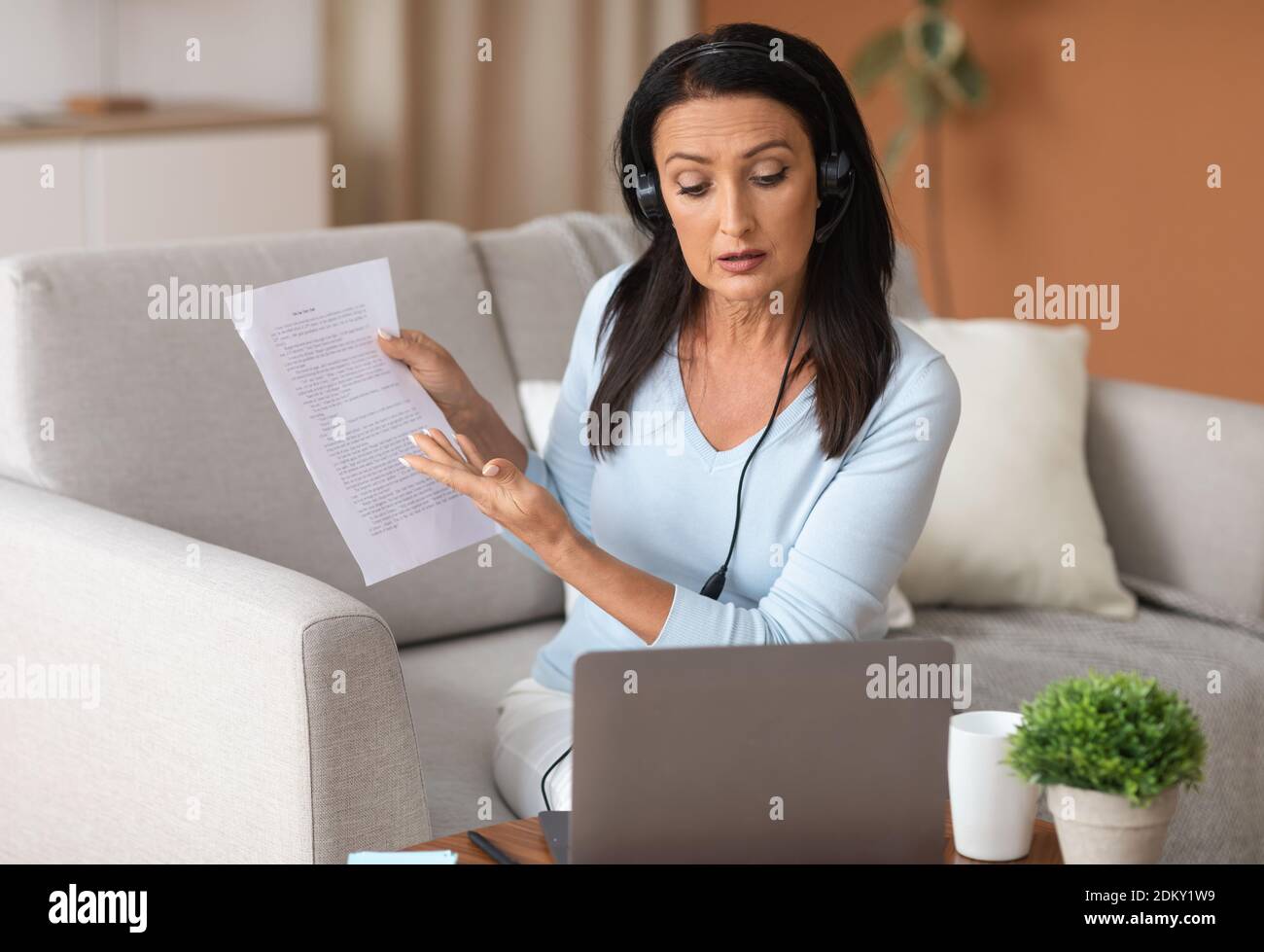Frau im Headset sitzt am Schreibtisch, mit Videoclip am Computer Stockfoto