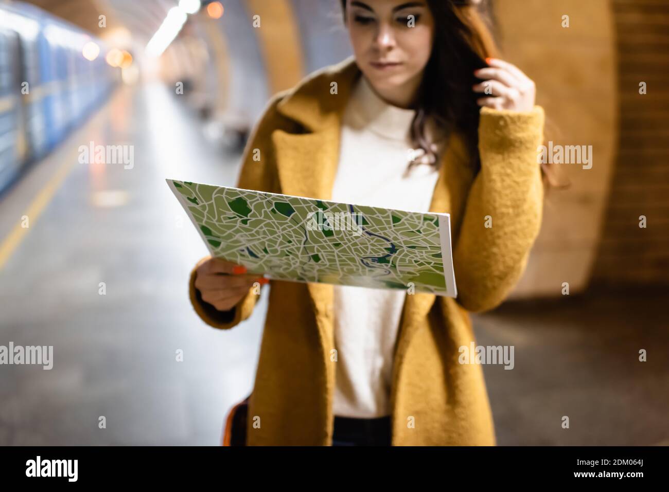 Junge Frau im Herbst Mantel Studium Stadtplan auf U-Bahn Plattform Stockfoto