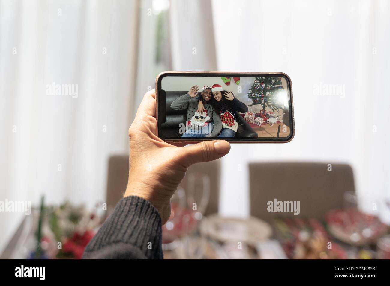 Videoanruf mit Familie online in der weihnachtszeit, Hand hält das Smartphone, Vater schaut die Söhne auf Lockdown. Familien- und Technologiekonzept. Stockfoto