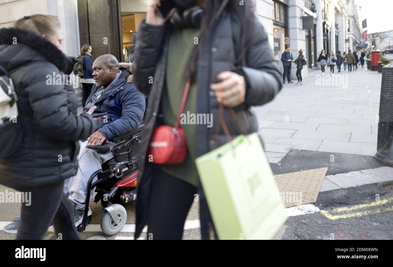 London, England, Großbritannien. Mann im Rollstuhl Weihnachtseinkäufe in der Regent Street, Dezember 2020 während der COVID Pandemie Stockfoto
