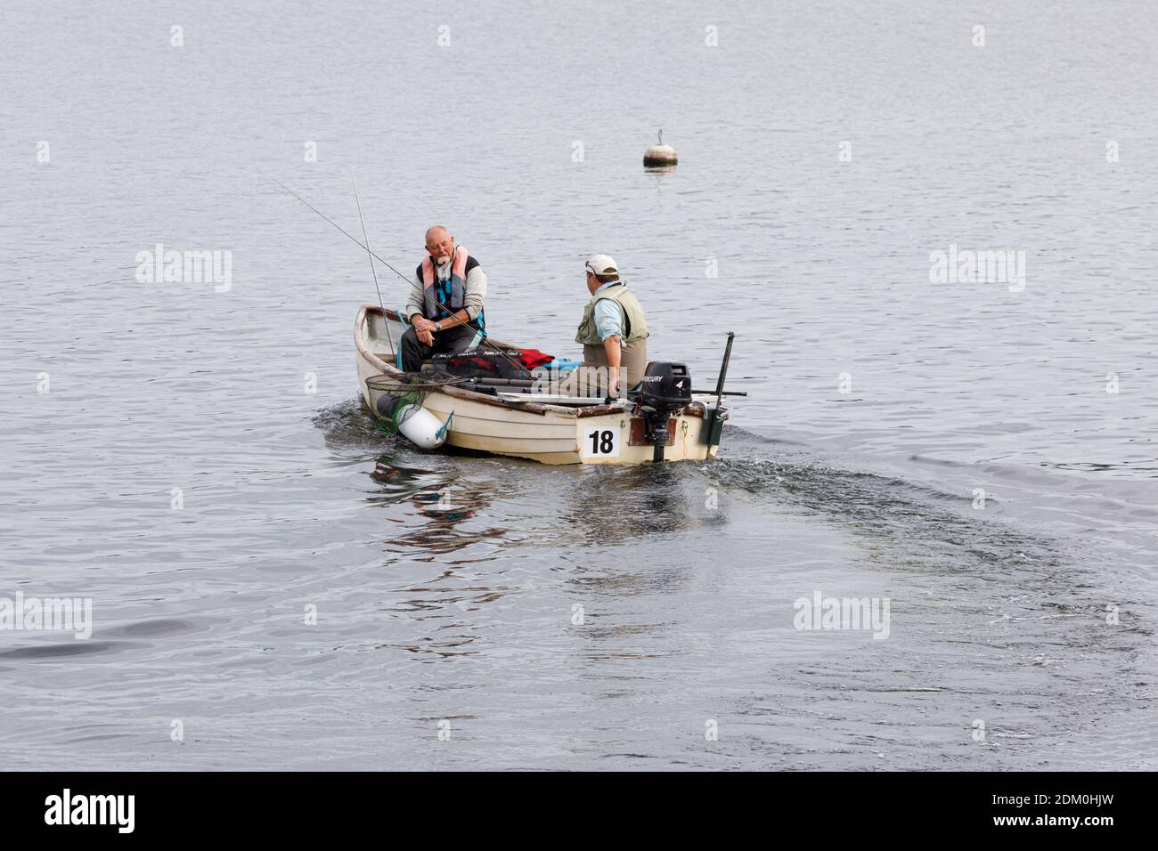 Draycote, Warwickshire, UK - 29/07/20: Zwei männliche Angler in einem kleinen Boot mit einem Außenbordmotor segeln ab, um auf dem Draycote Wasserreservoir zu fischen. Stockfoto
