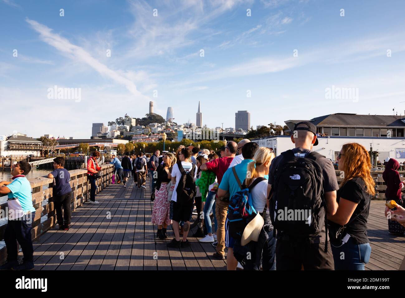 Passagiere, die auf die Fähre von San Francisco nach Oakland warten, stehen an Pier 41 in der Sonne an. San Francisco, Kalifornien Vereinigte Staaten von Amerika Stockfoto