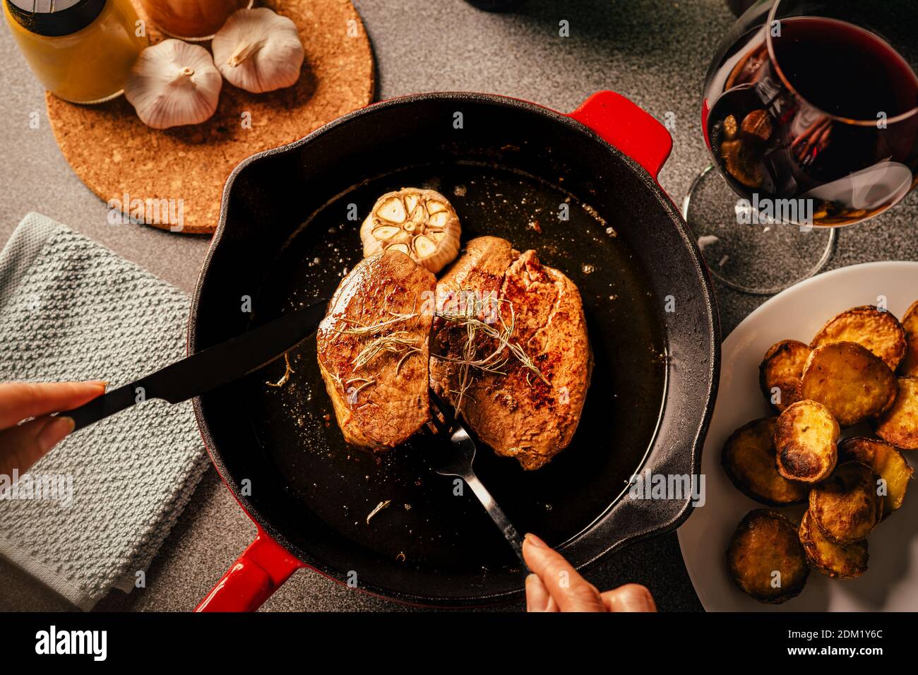 Steak Abendessen Vorbereitung.Weibliche Hände servieren und dekorieren einen besonderen Anlass Gourmet-Mahlzeit. Filet Mignon und gebackene Kartoffeln mit geröstetem Knoblauch und Stockfoto