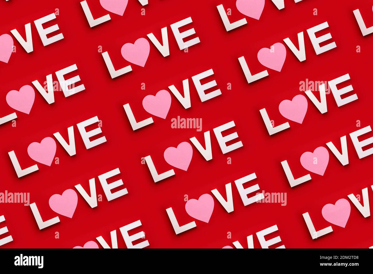 Alles Liebe zum Valentinstag. Das Wort Liebe in weißem Holz mit einem rosa Herz auf einem roten Hintergrund.Valentinstag Konzept Stockfoto