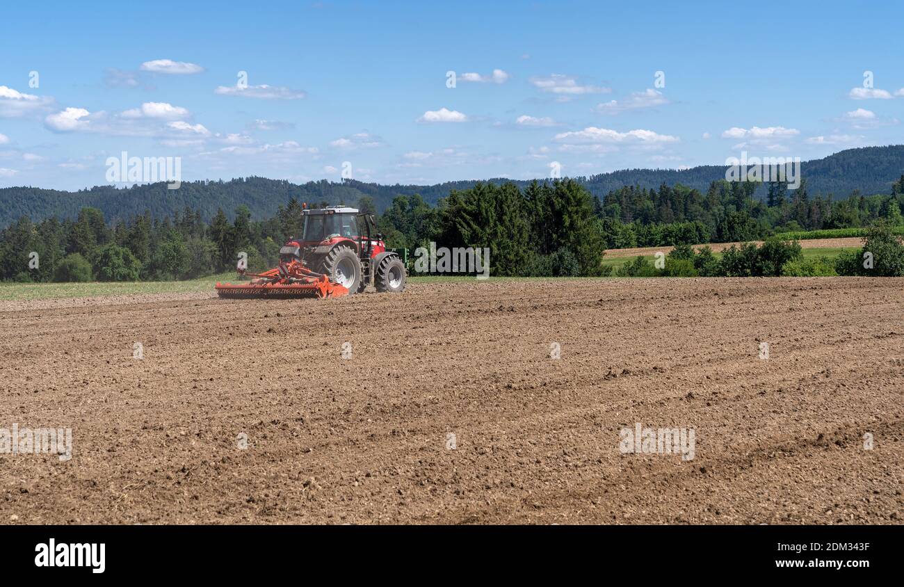 Traktor, während die braune Erde in einem Feld erschütternd Stockfoto