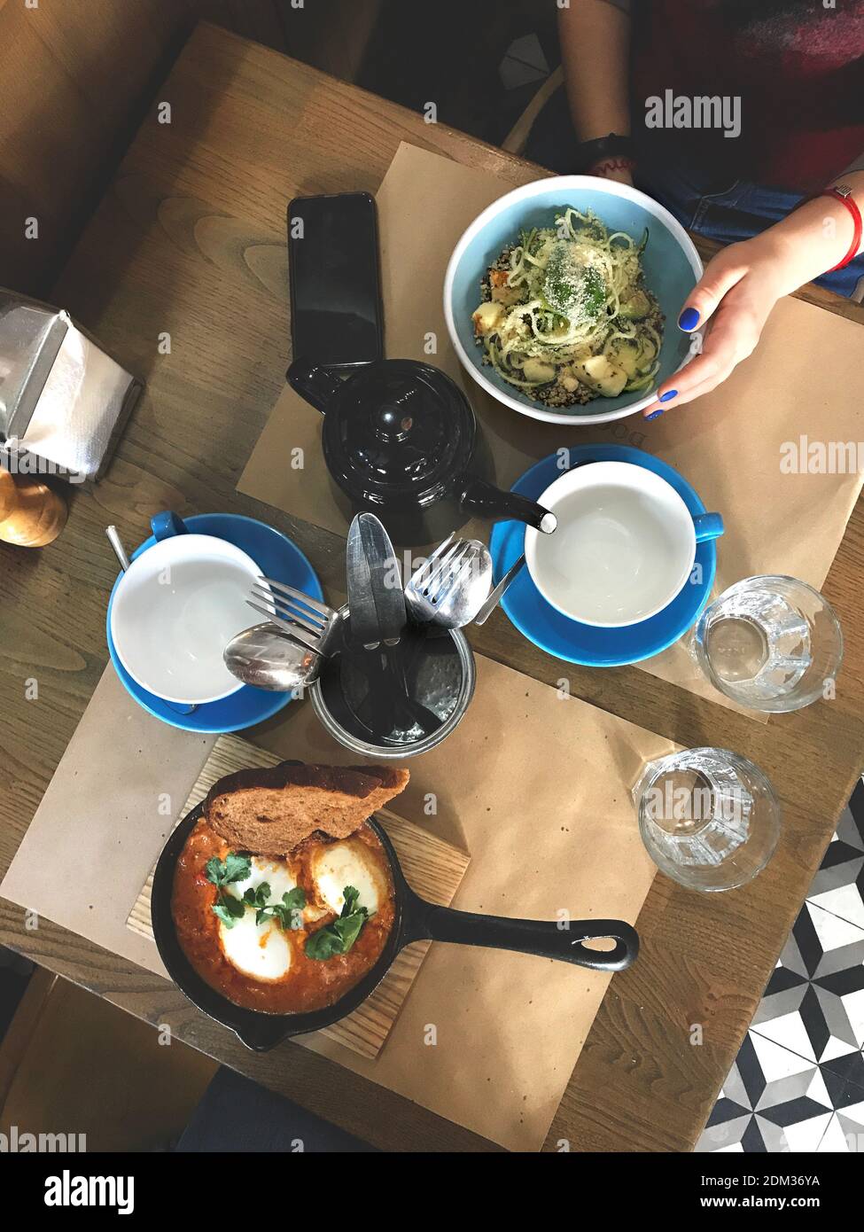 Gemütliches Abendessen im Café mit einem Freund. Draufsicht auf zwei Teller mit Zuccini-Spagetti und Shakshuka Stockfoto