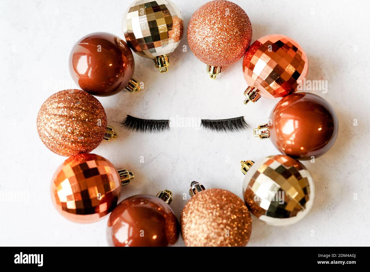 Falsche Wimpern mit goldenen Weihnachtskugeln. Make-Up-Konzept Stockfoto