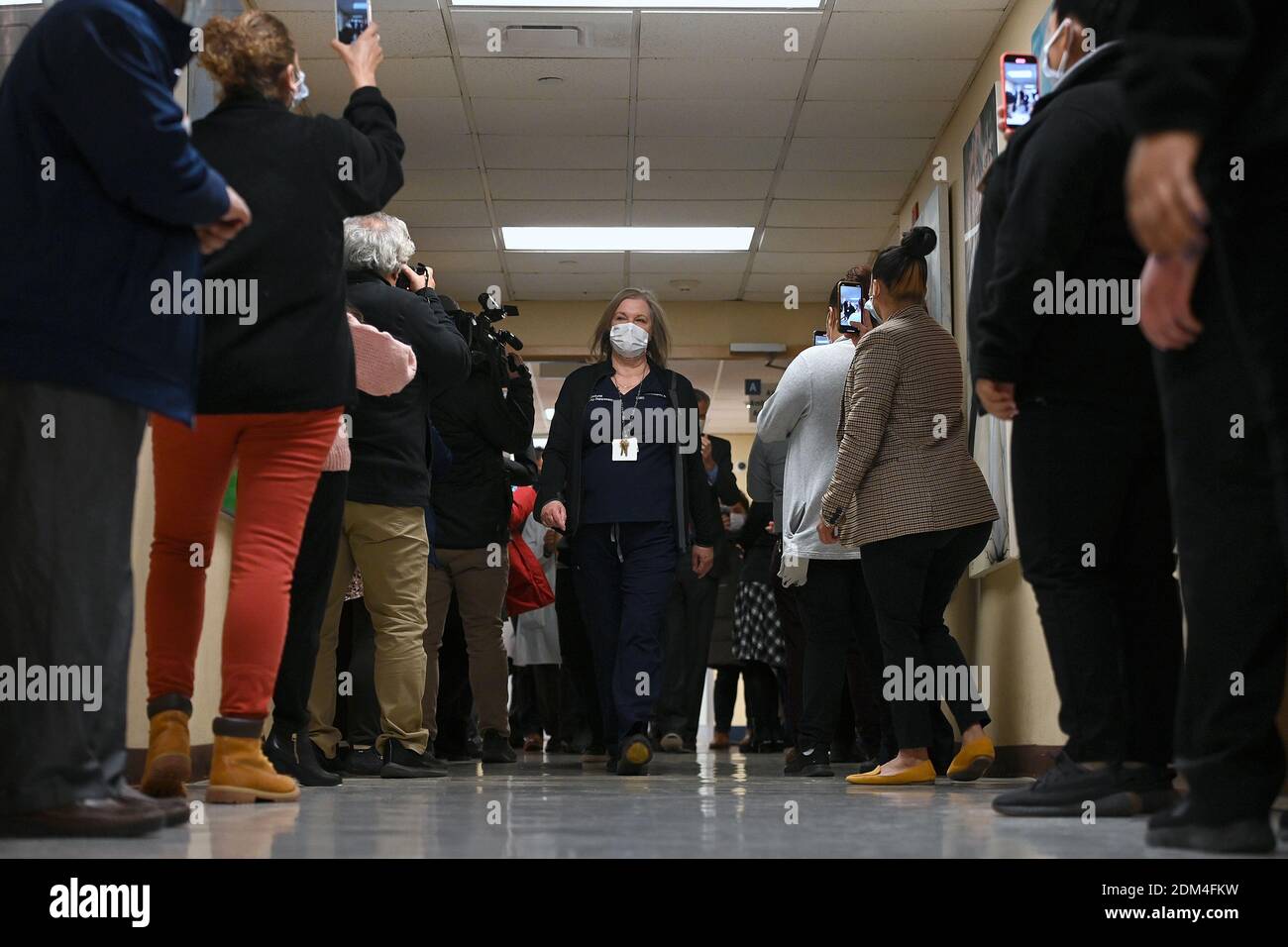 New York, USA. Dezember 2020. Medizinische Arbeiten jubeln, als die Assistentin der Notarztärztin Veronica Delgado einen Krankenhausflur hinuntergeht, nachdem sie die erste Dosis des Impfstoffs Pfizer-BioNTech COVID-19 an den NYC Health Hospitals/Elmhurst im Stadtteil Queens von New York City, NY, 16. Dezember 2020 erhalten hat. NYC Health Hospitals/Elmhurst ist das erste öffentliche Krankenhaus in New York City, das seine Mitarbeiter im Gesundheitswesen gegen das Coronavirus geimpft hat und plant, alle wichtigen medizinischen Fachkräfte innerhalb von 3 Wochen impfen zu lassen. (Foto von Anthony Behar/Sipa USA) Quelle: SIPA USA/Alamy Live News Stockfoto