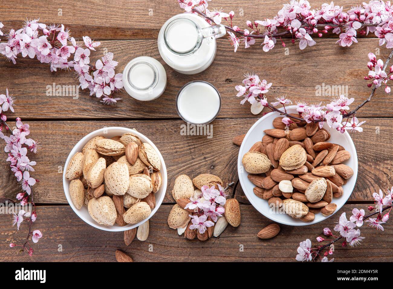 Mandeln, Mandeln, Milch und Mandelblüten auf Holzbasis. Draufsicht. Stockfoto