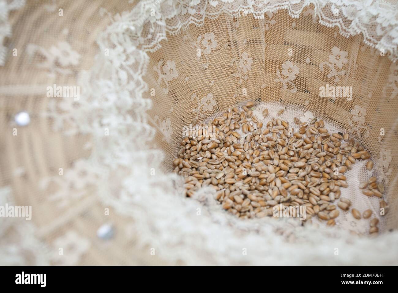 Eine Nahaufnahme eines Weizenkorns in einem Weidenkorb Gefüttert mit Mesh für eine Hochzeitszeremonie Stockfoto